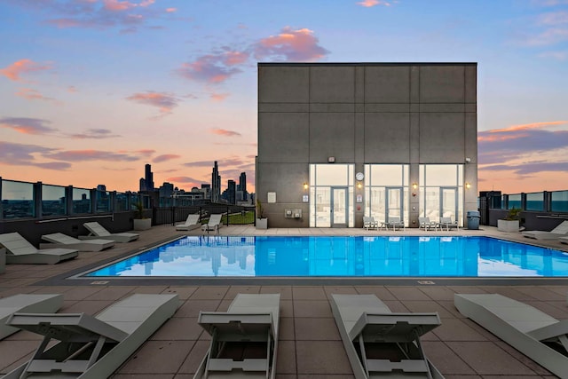 pool at dusk featuring a patio