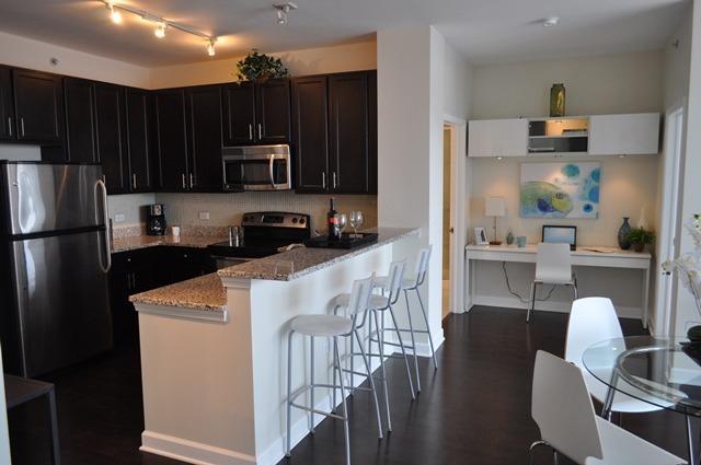 kitchen featuring a kitchen bar, light stone counters, built in desk, appliances with stainless steel finishes, and dark hardwood / wood-style floors