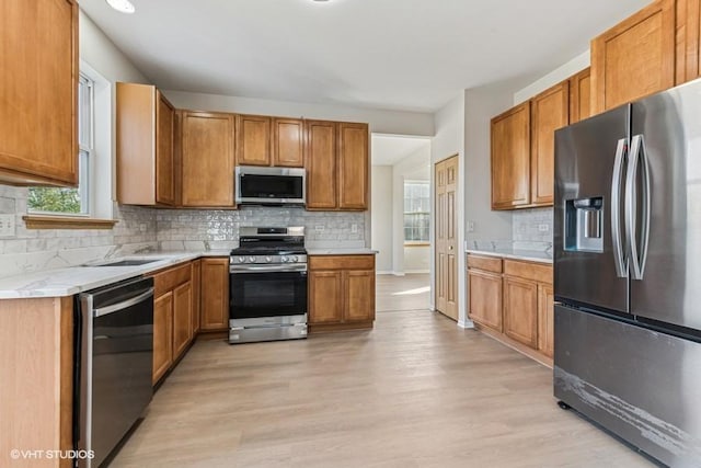 kitchen featuring decorative backsplash, light hardwood / wood-style floors, sink, and stainless steel appliances