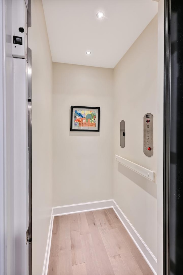 laundry room with light wood-type flooring and elevator