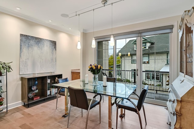 dining room featuring hardwood / wood-style flooring, track lighting, and crown molding