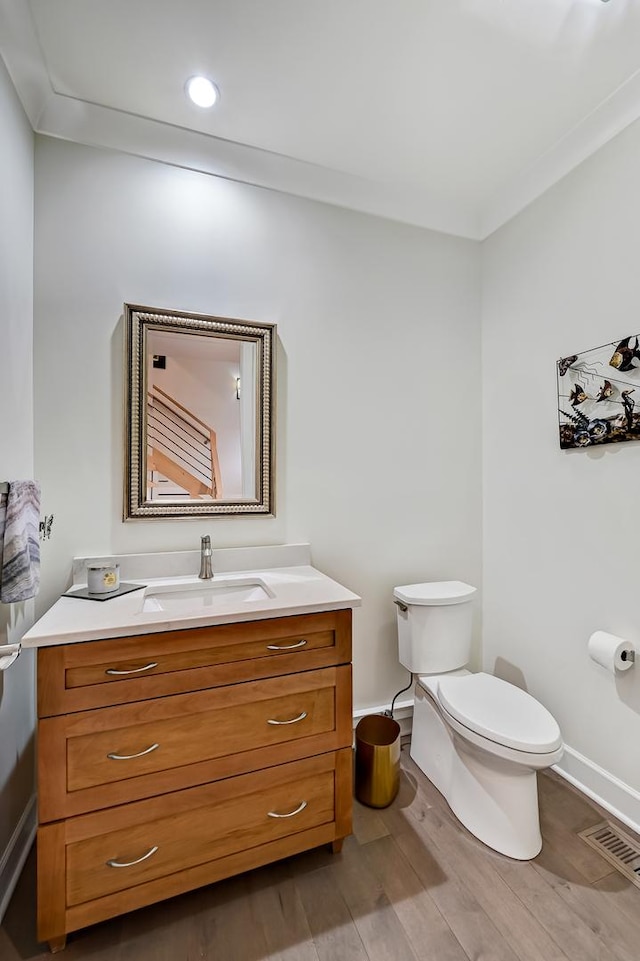 bathroom with hardwood / wood-style floors, vanity, toilet, and crown molding