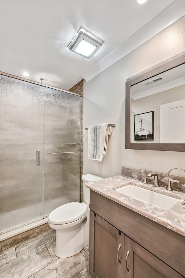 bathroom with vanity, ornamental molding, an enclosed shower, and toilet