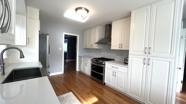 kitchen featuring wall chimney exhaust hood, stainless steel appliances, sink, white cabinets, and dark hardwood / wood-style floors