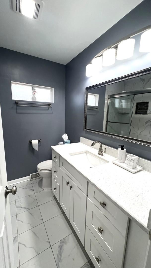 bathroom featuring vanity, toilet, and an enclosed shower