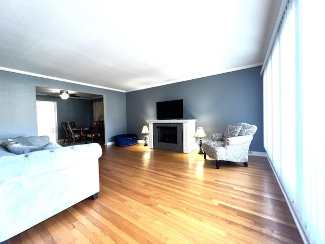 living room with hardwood / wood-style flooring, ceiling fan, and crown molding