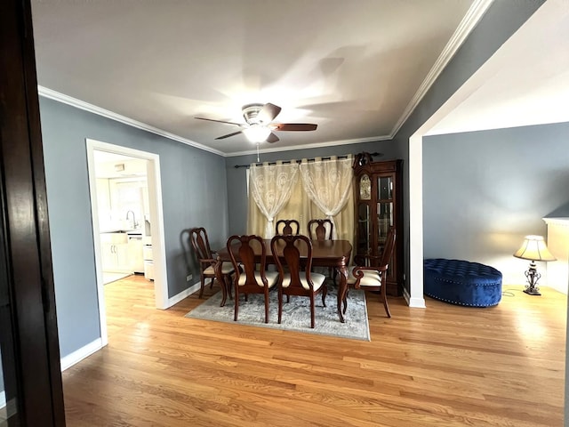 dining space featuring ceiling fan, light hardwood / wood-style floors, ornamental molding, and sink