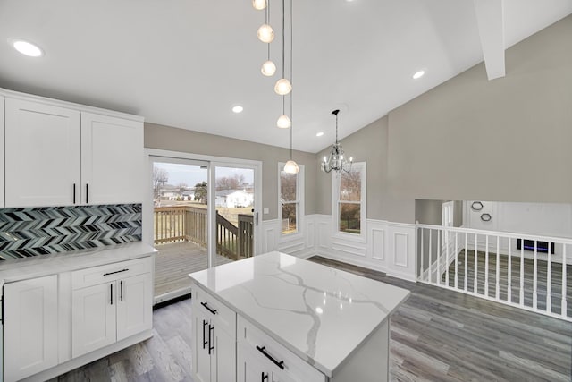 kitchen featuring a center island, white cabinets, and vaulted ceiling