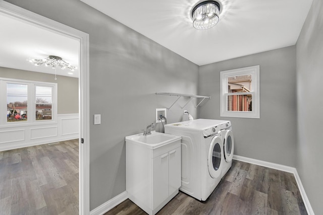 laundry area with cabinets, hardwood / wood-style flooring, washer and clothes dryer, and sink