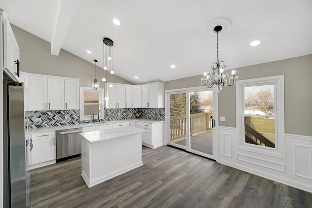 kitchen featuring stainless steel appliances, a kitchen island, backsplash, decorative light fixtures, and white cabinets