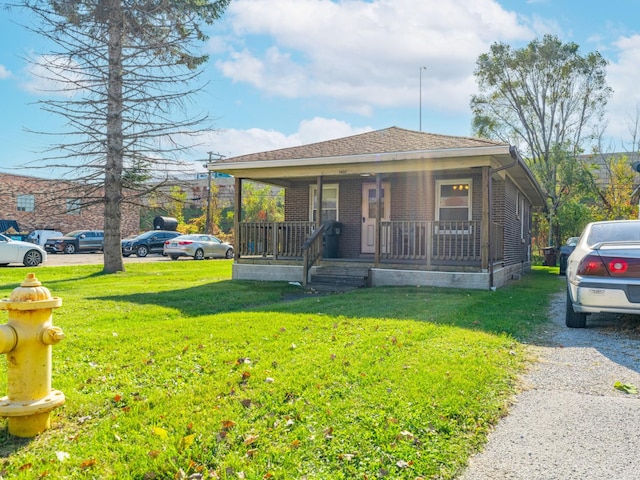 bungalow featuring covered porch and a front yard