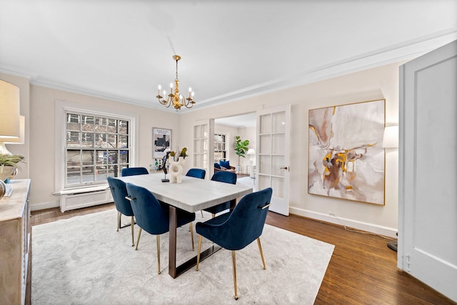 dining space featuring ornamental molding, a chandelier, baseboards, and wood finished floors