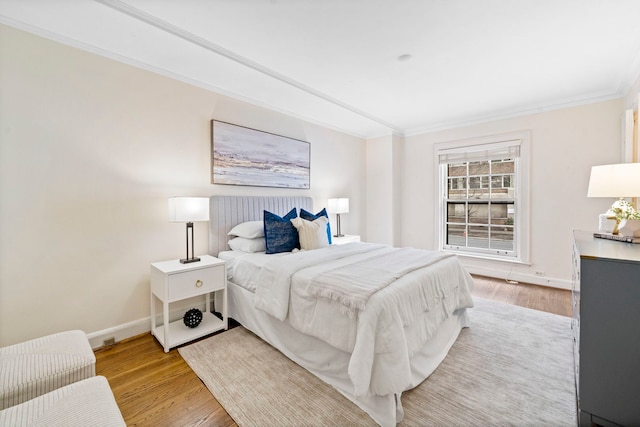 bedroom featuring baseboards, ornamental molding, and light wood-style floors