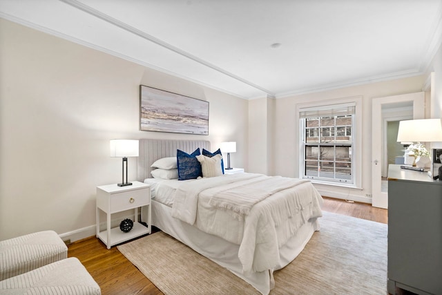 bedroom with light wood-style floors, crown molding, and baseboards