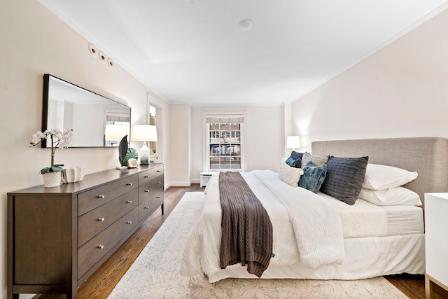 bedroom with baseboards, ornamental molding, and wood finished floors