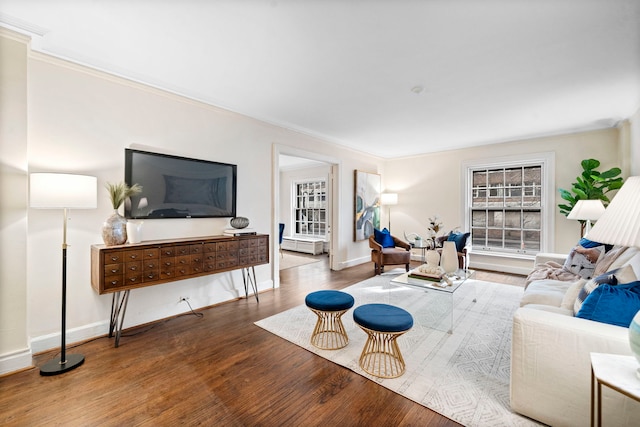 living area with ornamental molding, wood finished floors, and baseboards