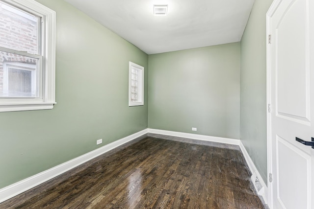 empty room featuring a wealth of natural light and dark hardwood / wood-style flooring