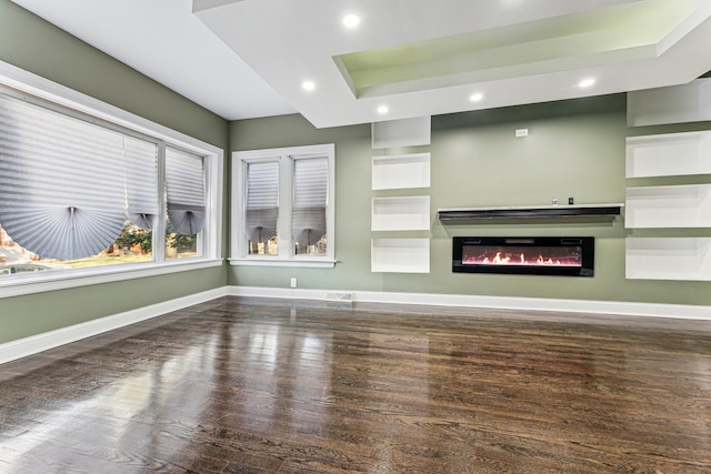 unfurnished living room featuring baseboards, a glass covered fireplace, dark wood finished floors, and recessed lighting