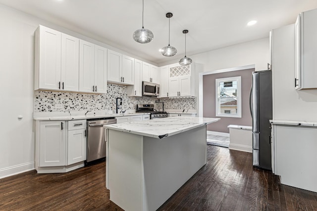 kitchen featuring appliances with stainless steel finishes, white cabinets, dark hardwood / wood-style floors, a kitchen island, and hanging light fixtures