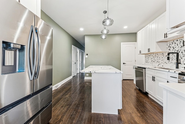 kitchen with white cabinets, a kitchen island, stainless steel appliances, and dark wood-type flooring