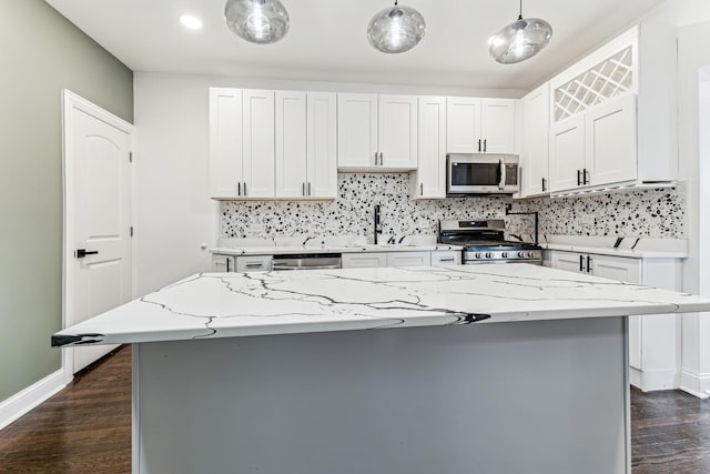 kitchen with white cabinets, decorative light fixtures, stainless steel appliances, and dark wood-type flooring