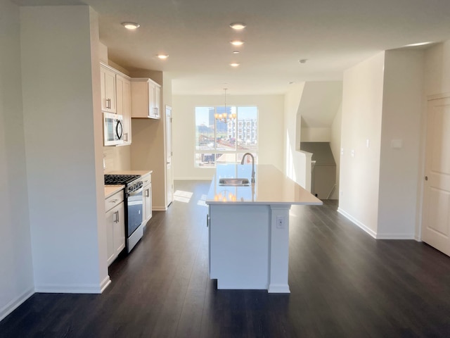 kitchen featuring gas stove, dark wood-type flooring, sink, white cabinetry, and an island with sink