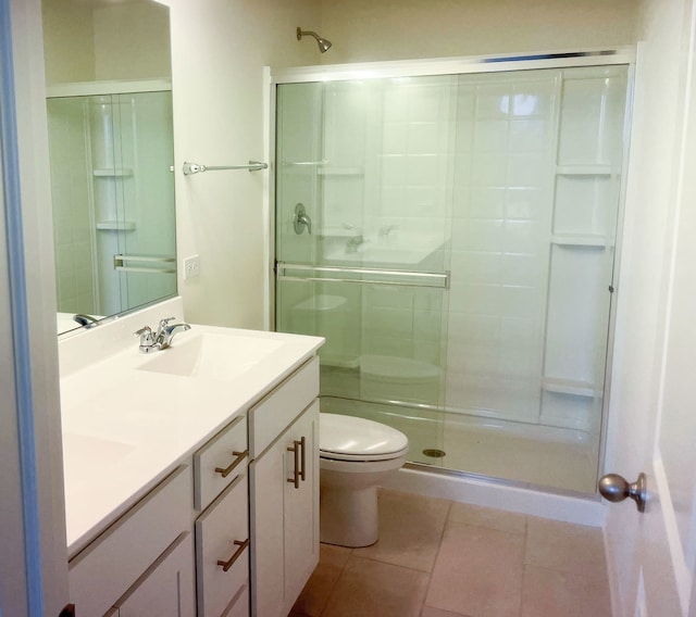 bathroom featuring tile patterned flooring, vanity, a shower with shower door, and toilet