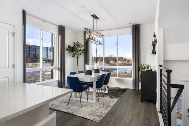 dining space featuring a water view, dark hardwood / wood-style flooring, a wealth of natural light, and a chandelier