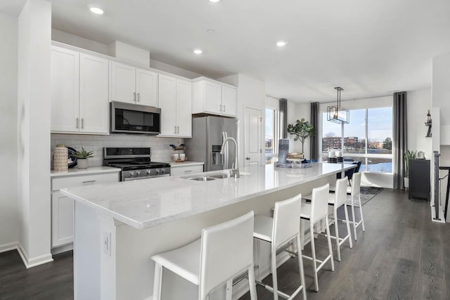 kitchen featuring white cabinets, stainless steel appliances, and an island with sink