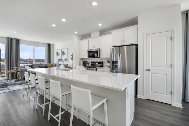 kitchen with sink, stainless steel appliances, a spacious island, a breakfast bar, and white cabinets