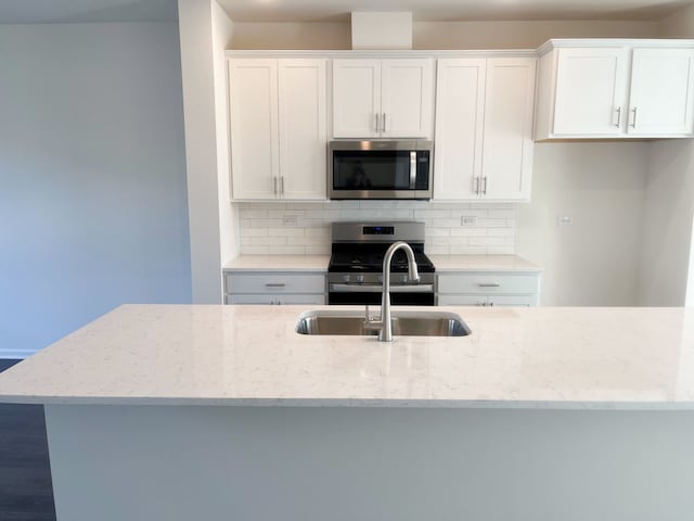 kitchen featuring light stone countertops, white cabinetry, appliances with stainless steel finishes, and tasteful backsplash