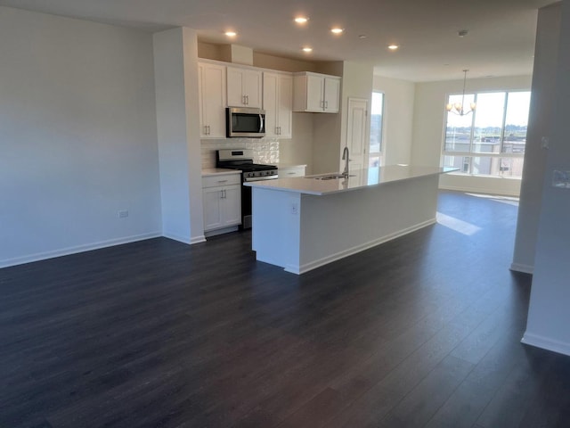 kitchen with white cabinetry, a kitchen island with sink, appliances with stainless steel finishes, and dark wood-type flooring