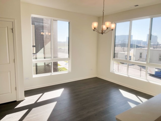 unfurnished dining area featuring plenty of natural light, dark wood-type flooring, and an inviting chandelier