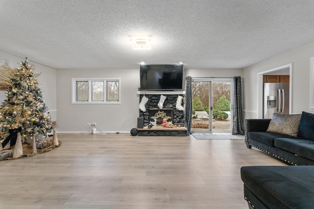 living room featuring a fireplace, a textured ceiling, and light hardwood / wood-style flooring