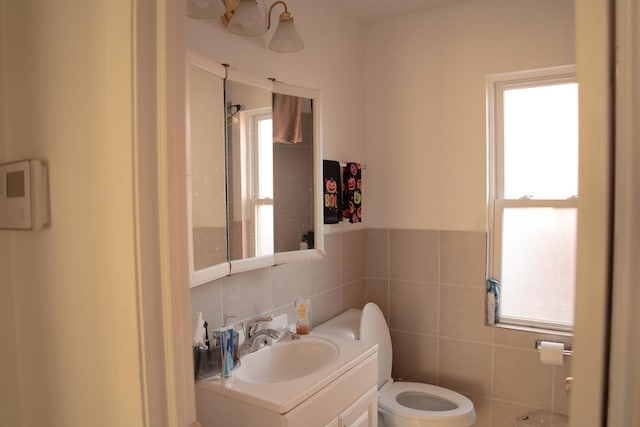 bathroom featuring vanity, toilet, and tile walls