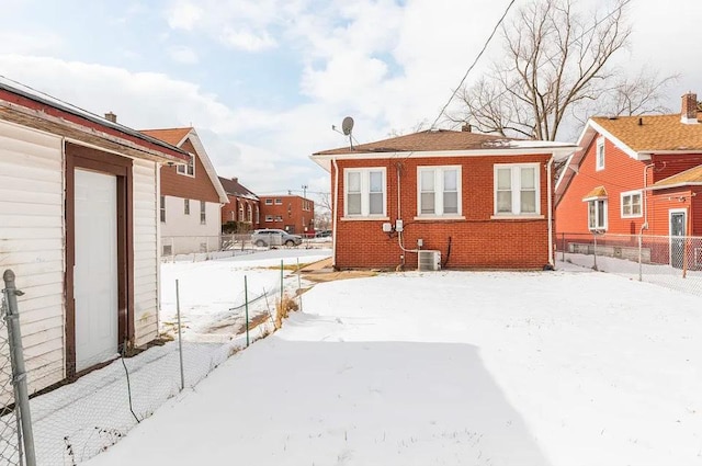 snow covered back of property featuring central AC unit