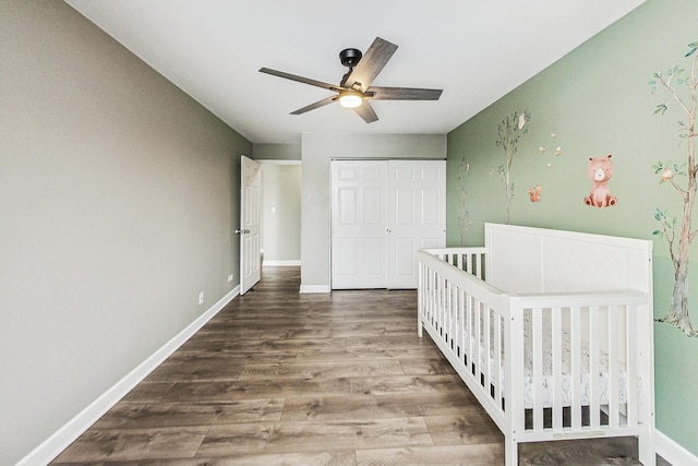 unfurnished bedroom with ceiling fan, a closet, a nursery area, and hardwood / wood-style flooring