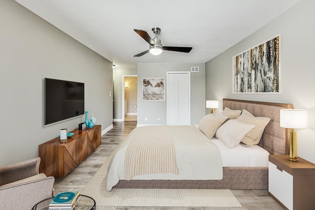 bedroom with ceiling fan, a closet, and light hardwood / wood-style floors