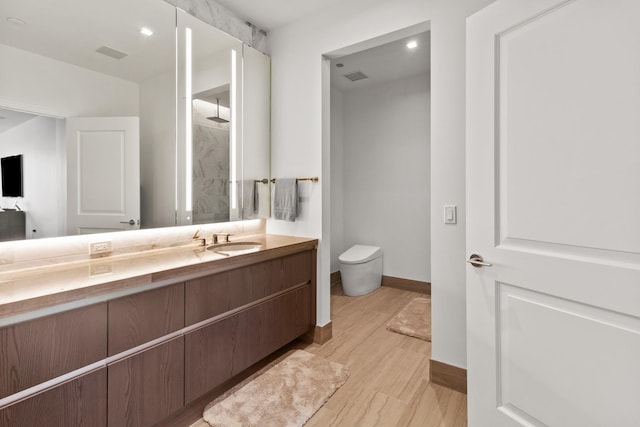 bathroom with hardwood / wood-style flooring, vanity, toilet, and walk in shower