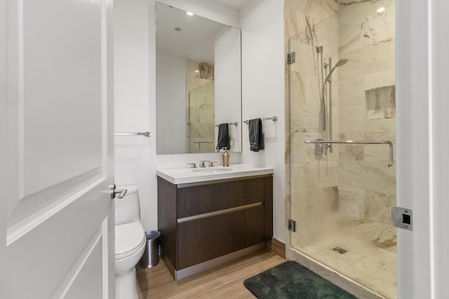 bathroom with hardwood / wood-style floors, vanity, toilet, and an enclosed shower