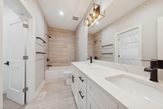 full bathroom with vanity, tiled shower / bath, and toilet