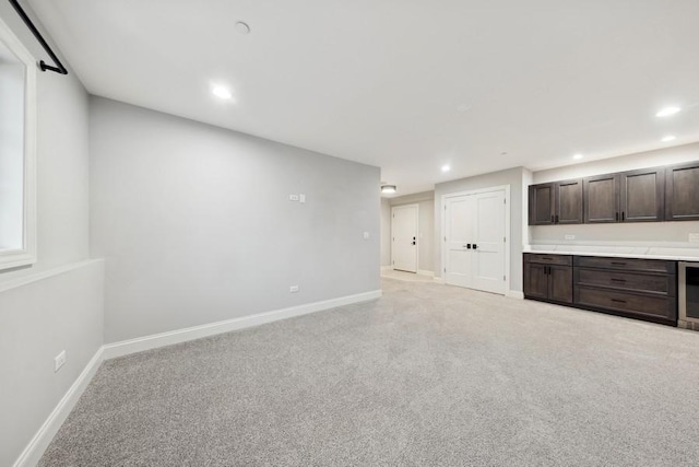 unfurnished living room featuring light colored carpet and beverage cooler