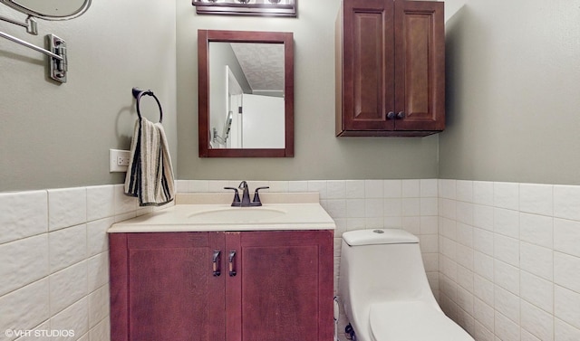 bathroom featuring vanity, toilet, and tile walls