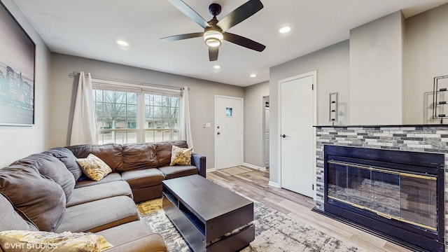 living room featuring ceiling fan, light hardwood / wood-style floors, and a fireplace