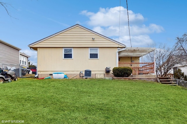 rear view of property with central air condition unit and a yard