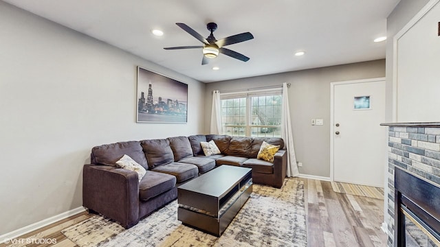 living room featuring light hardwood / wood-style floors, a brick fireplace, and ceiling fan