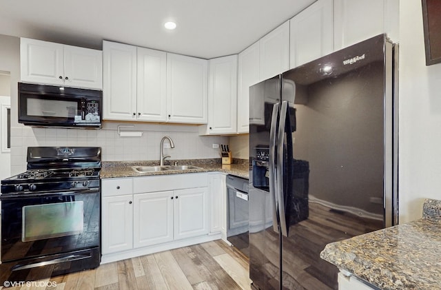 kitchen featuring dark stone counters, sink, black appliances, light hardwood / wood-style flooring, and white cabinetry