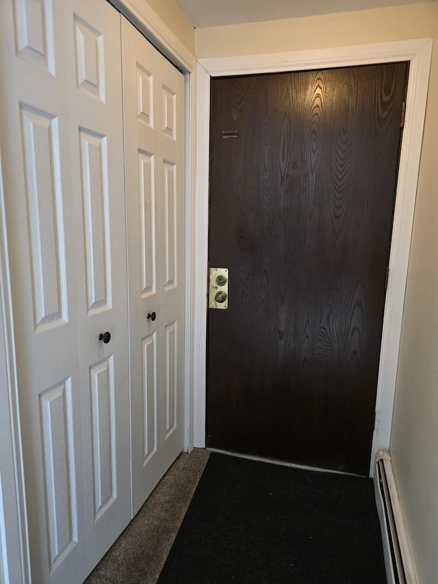 doorway to outside featuring a baseboard radiator and dark carpet