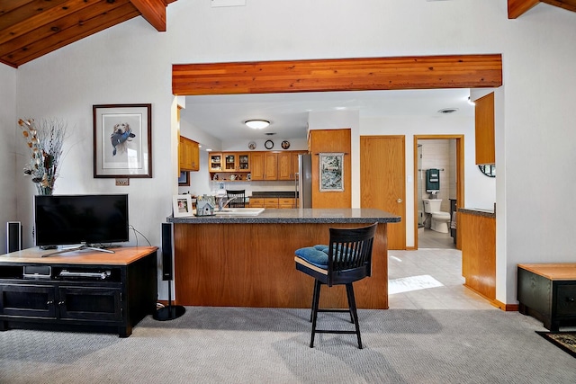 kitchen featuring wood ceiling, vaulted ceiling with beams, a kitchen breakfast bar, light colored carpet, and kitchen peninsula