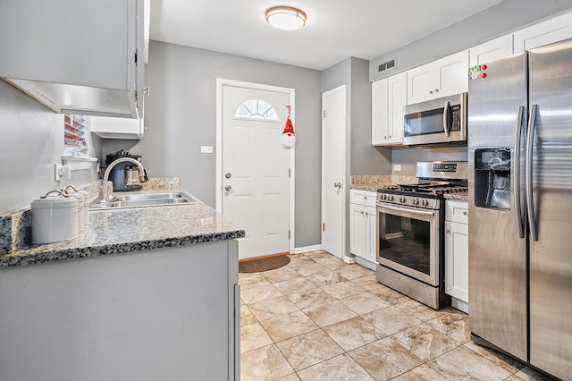 kitchen featuring sink, appliances with stainless steel finishes, white cabinetry, light stone counters, and a healthy amount of sunlight